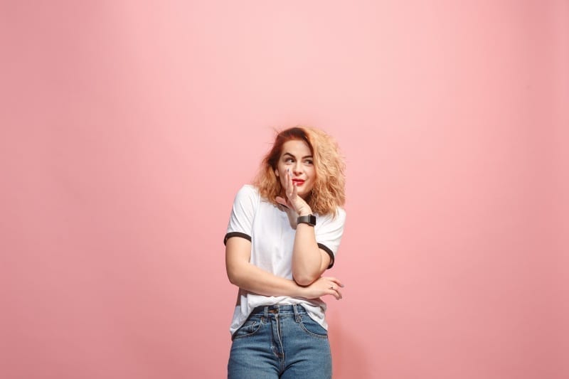 young woman whispering secret her hand pink background